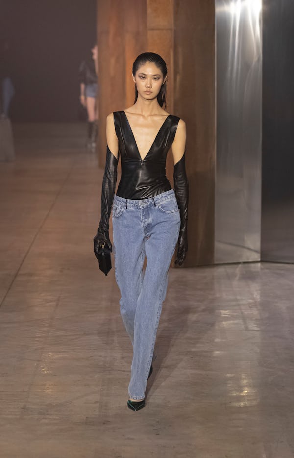 The model wears a night-out bodysuit paired with wide-leg denim from Bally Spring/Summer 2023 Collec...