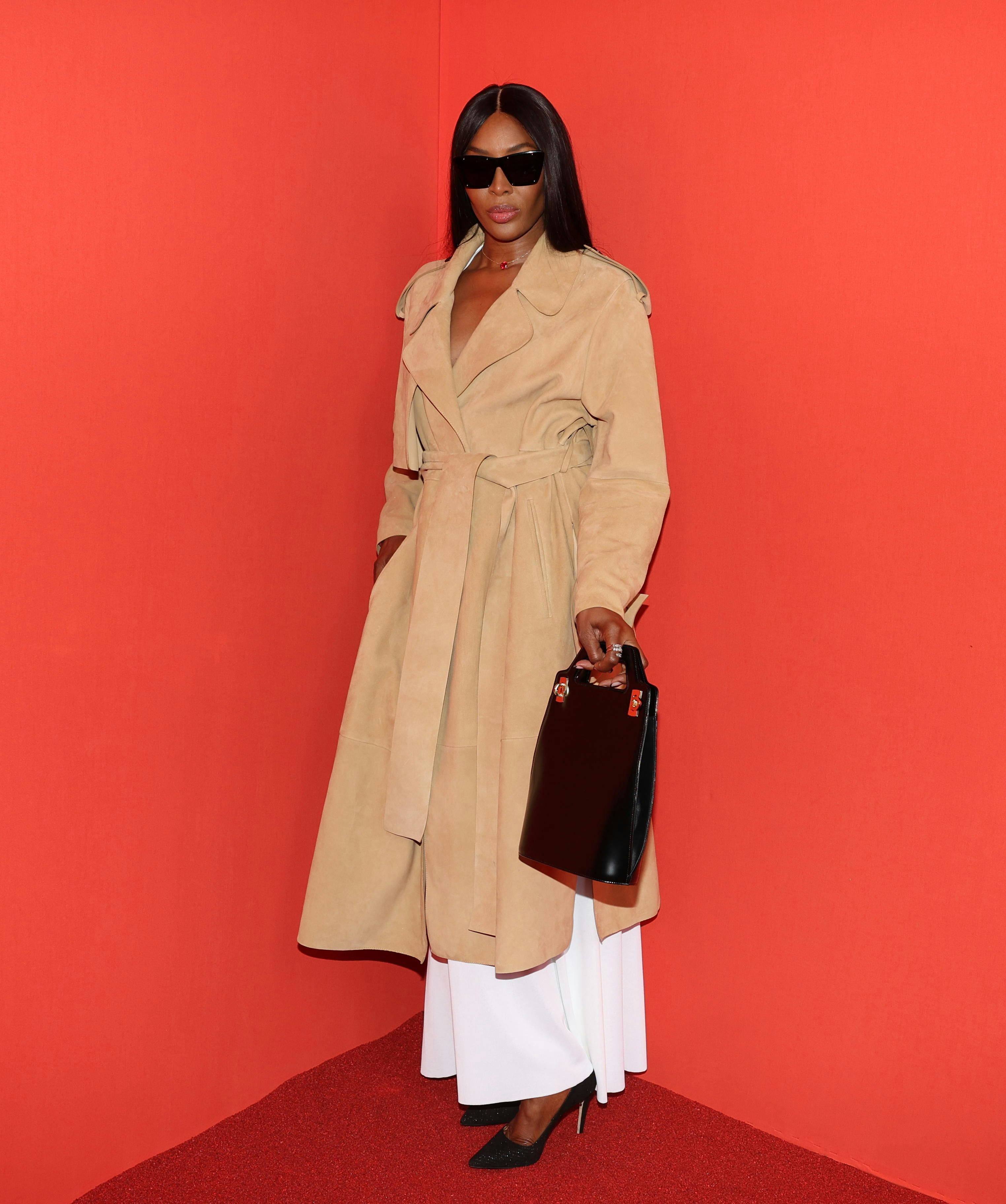 Naomi Campbell posing for a photo in a light brown coat at Milan Fashion Week