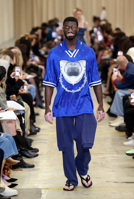 A male model walking the runway at the Burberry show during London Fashion Week September 2022 in a ...