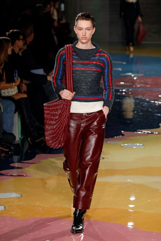A model walks the Bottega Veneta Spring 2023 runway in sweater and leather burgundy pants.