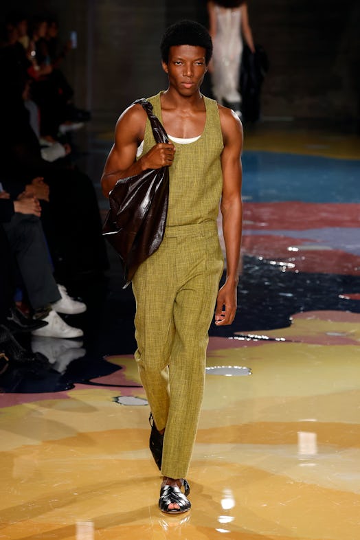 A male model walks the Bottega Veneta Spring 2023 runway in mustard green pants and top tank.