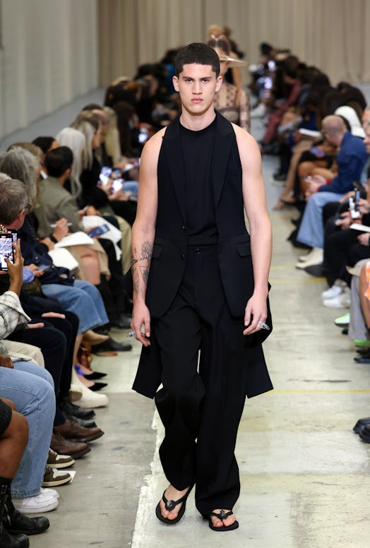 A male model walking the runway at the Burberry show during London Fashion Week in a black overall