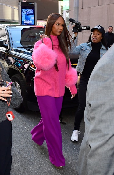 Iman wearing a bright pink fuzzy top and wide-legged purple pants