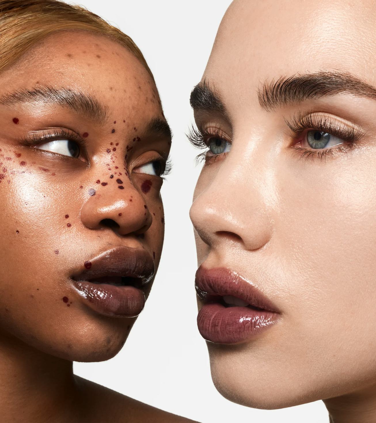 Two close-up portraits of diverse women, one with freckles and dark skin, the other with light skin ...