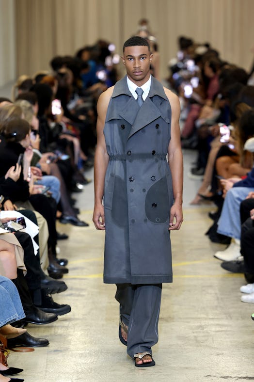A male model walking the runway at the Burberry show during London Fashion Week in a grey sleeveless...