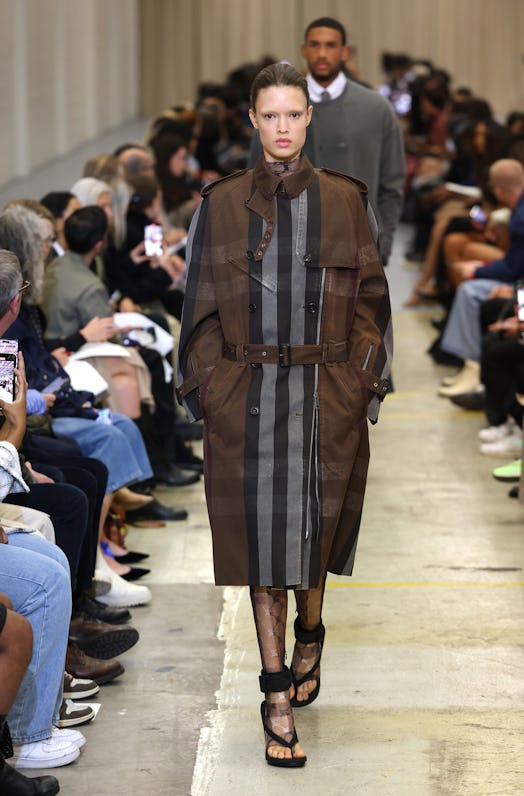 A female model walking the runway at the Burberry show during London Fashion Week in a plaid coat