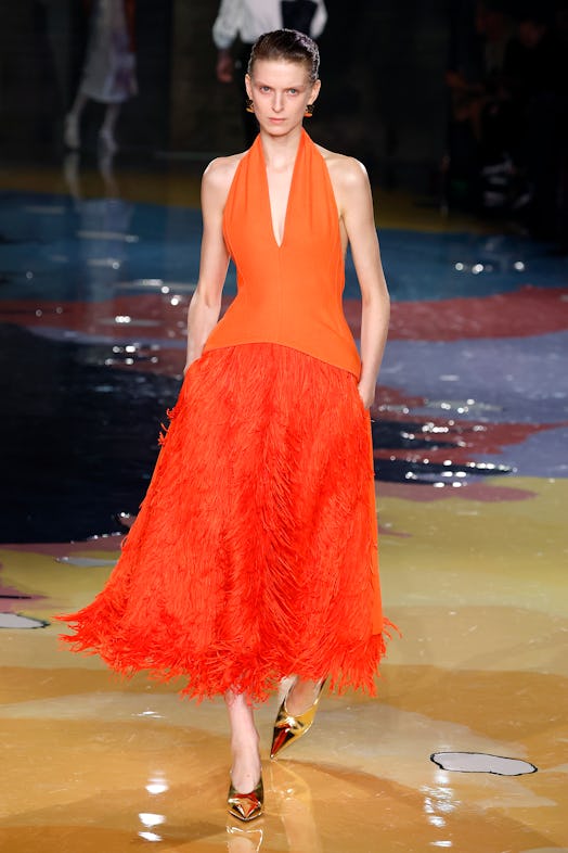 A model walks the Bottega Veneta Spring 2023 runway in an orange maxi dress as part of the Milan Fas...