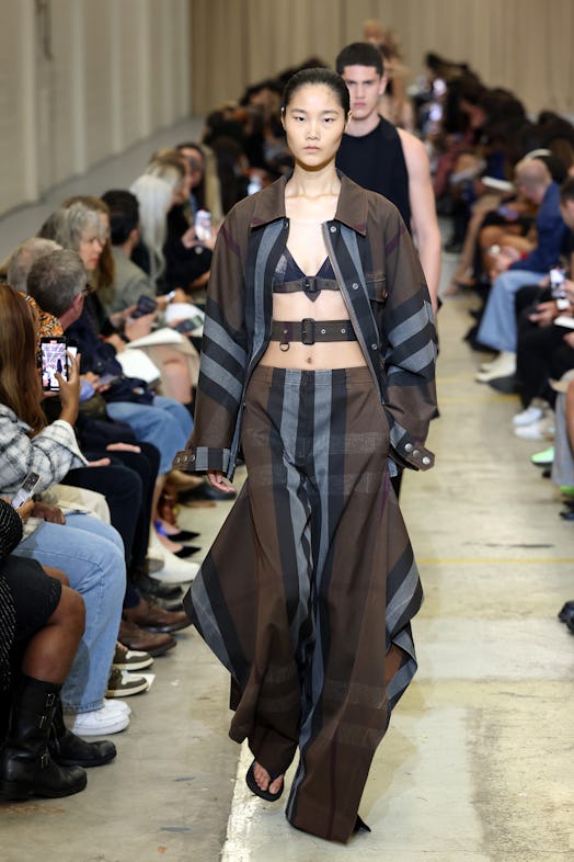 A female model walking the runway at the Burberry show during London Fashion Week in plaid pants and...