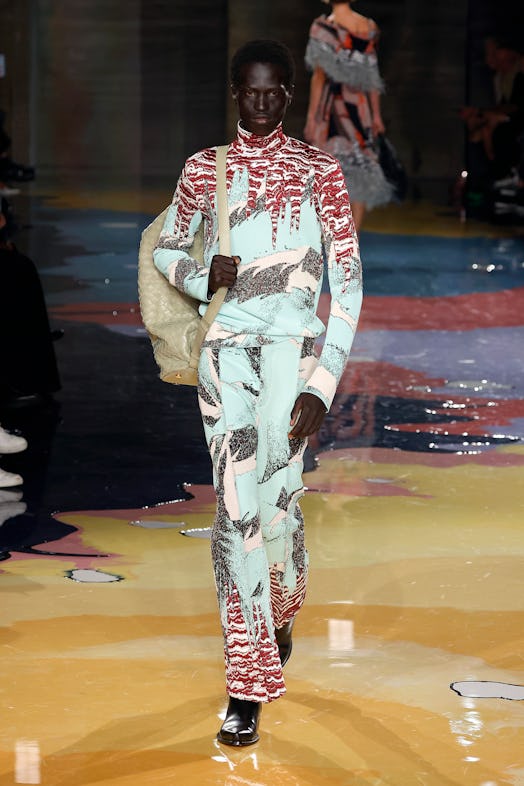 A model walks the Bottega Veneta Spring 2023 runway in multicolored printed trousers and turtleneck ...
