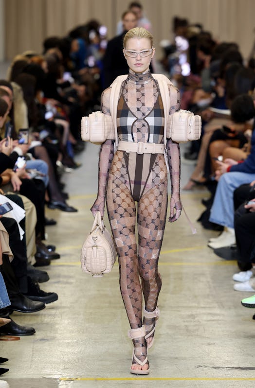 A female model walking the runway at the Burberry show during London Fashion Week in a see-through o...