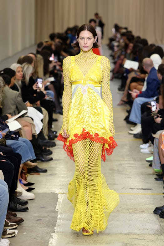 A female model walking the runway at the Burberry show during London Fashion Week in a yellow dress 