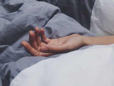 Close up of a hand surrounded by blankets in bed.