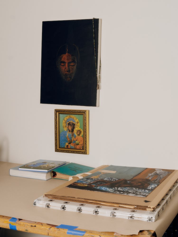 Danielle's desk in her studio with her references on top. A painting on the wall above her desk.