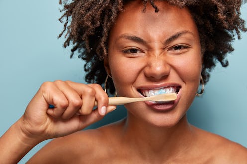 In this photo, a person brushes their teeth with a wooden toothbrush, much like one would for the be...
