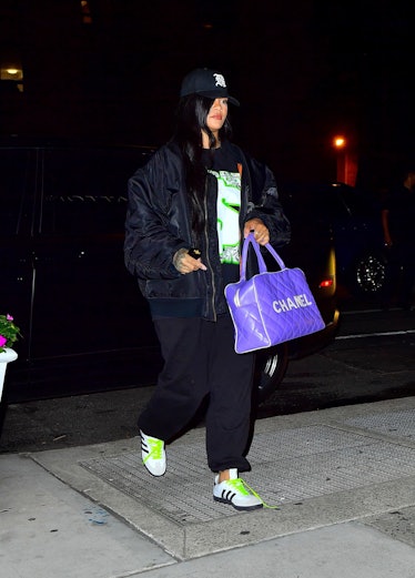 Rihanna wearing a black baseball cap and carrying a purple Chanel bag