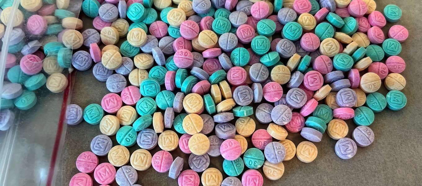 An assortment of colorful pills spilling out of a plastic bag. The DEA is warning parents about so-c...