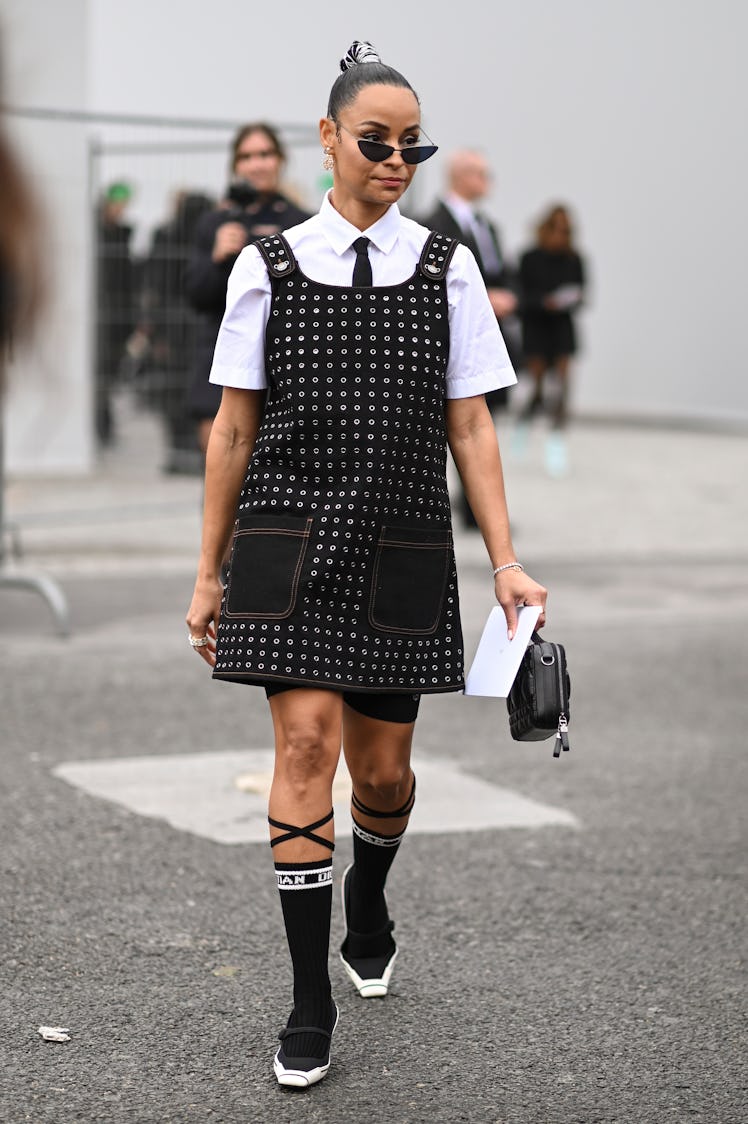 Sai de Silva is seen wearing a black and studded Dior dress, white shirt, black tie, Dior socks and ...