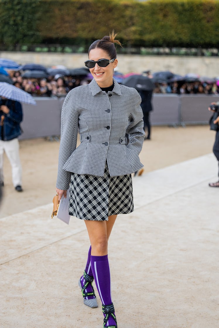 Gala Gonzalez wears grey pepita tailored blazer, checkered black white skirt, purple knee socks, hee...