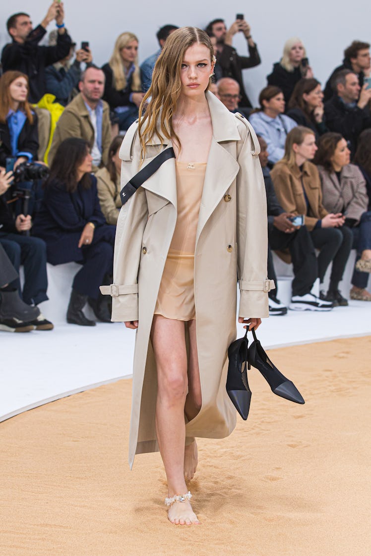 A model walking in Courrèges nude coat and beige short dress at the Paris Fashion Week Spring 2023