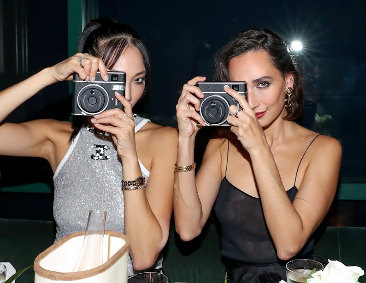 Rebecca Dayan and Park posing and holding film cameras in hands.