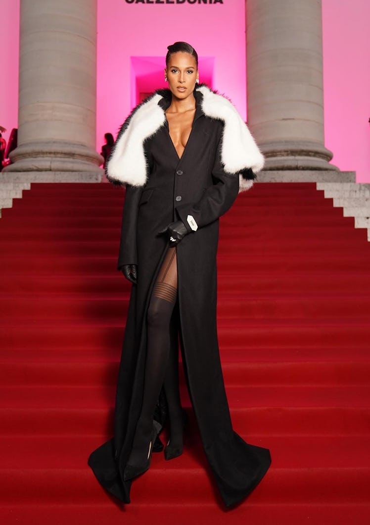 Cindy Bruna wearing a black gown with a high slit and white fur accents at a Calzedonia event