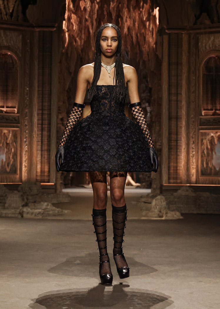 A model wearing Dior black lace cocktail dress with black gloves and boots at the Paris Fashion Week...