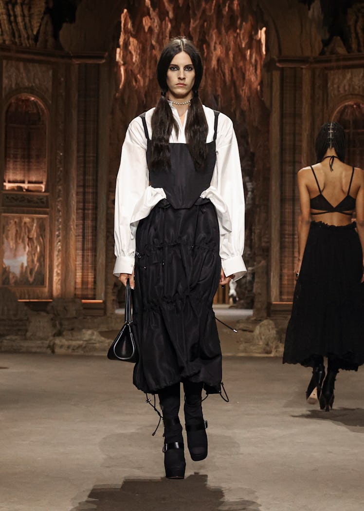 A model in Dior black corset top & skirt, white oversized shirt, and black platformed boots at the P...