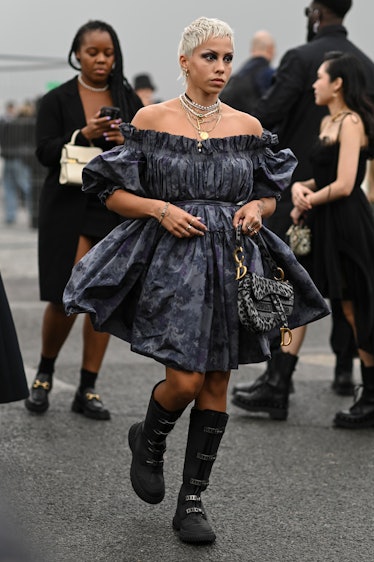 Poppy Ajudha is seen wearing a Dior floral gray dress and black boots with a Dior animal print bag o...