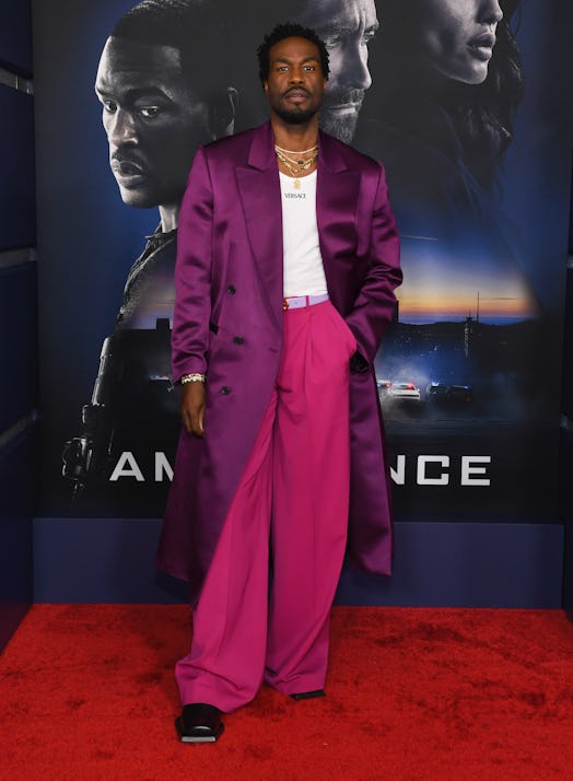 Yahya Abdul-Mateen II wearing a purple jacket and magenta pants on a red carpet