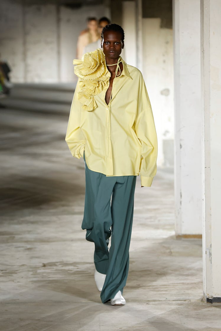 A model in Dries Van Noten’s oversized yellow shirt with shoulder flowers and green pants at Paris F...
