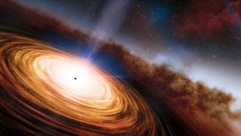 Color image of an orange-white disc of gas around a supermassive black hole.