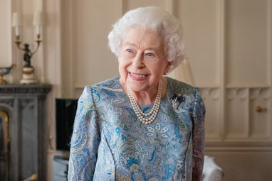Queen Elizabeth smiling in blue outfit.