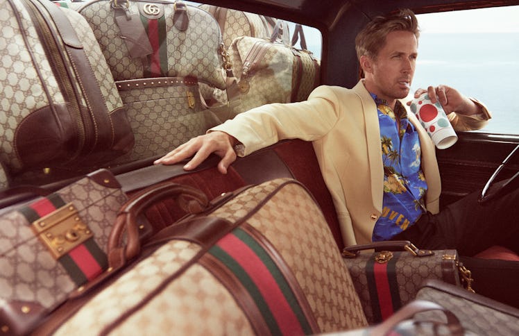 Ryan Gosling sipping a soda in a car surrounded by Gucci luggage