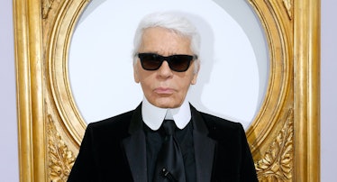 Karl Lagerfeld wearing sunglasses and standing in front of a gilded frame