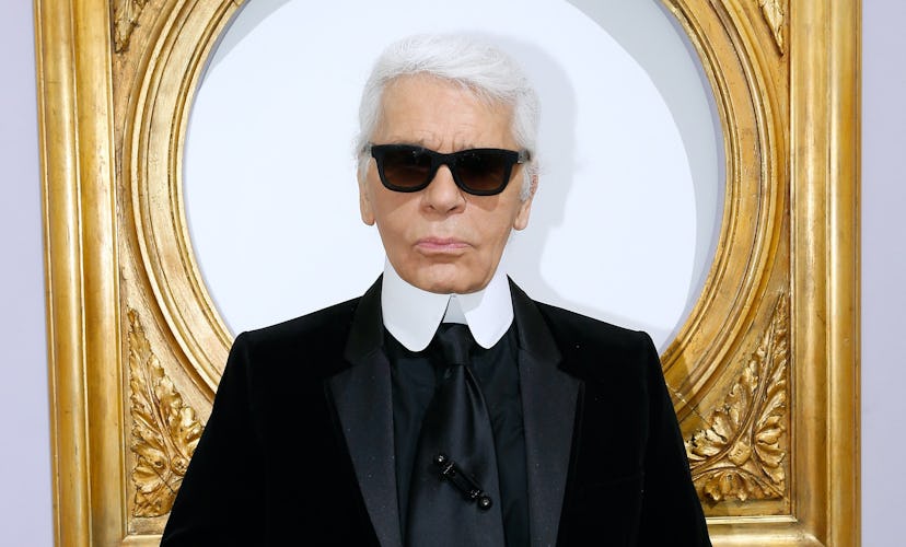 Karl Lagerfeld wearing sunglasses and standing in front of a gilded frame