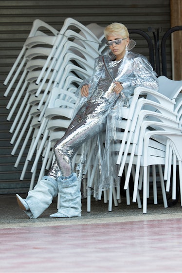 Iris Law wearing silver and leaning on a stack of chairs in her Alexandre Vauthier campaign
