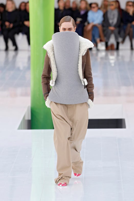 A model in a grey sweater with a cardboard-like facade obscuring the face at Loewe Spring 2023 Paris...