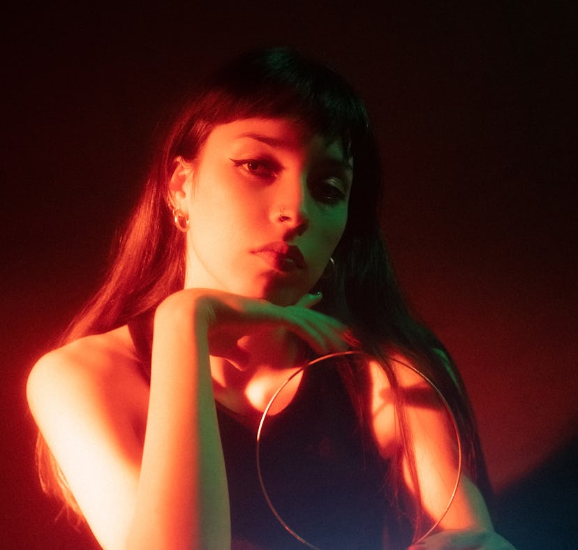 Young woman illuminated by a neon light with a TV monitor as Pluto retrograde 2022 ends.