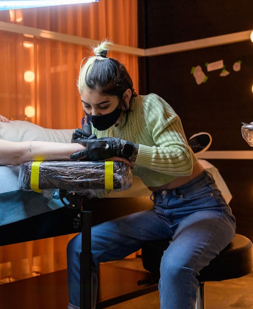 Stock image of a tattoo artist giving someone a tattoo