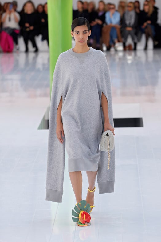 A model walking the runway in a huge grey sweatshirt used as a dress at Loewe Spring 2023 Paris Fash...