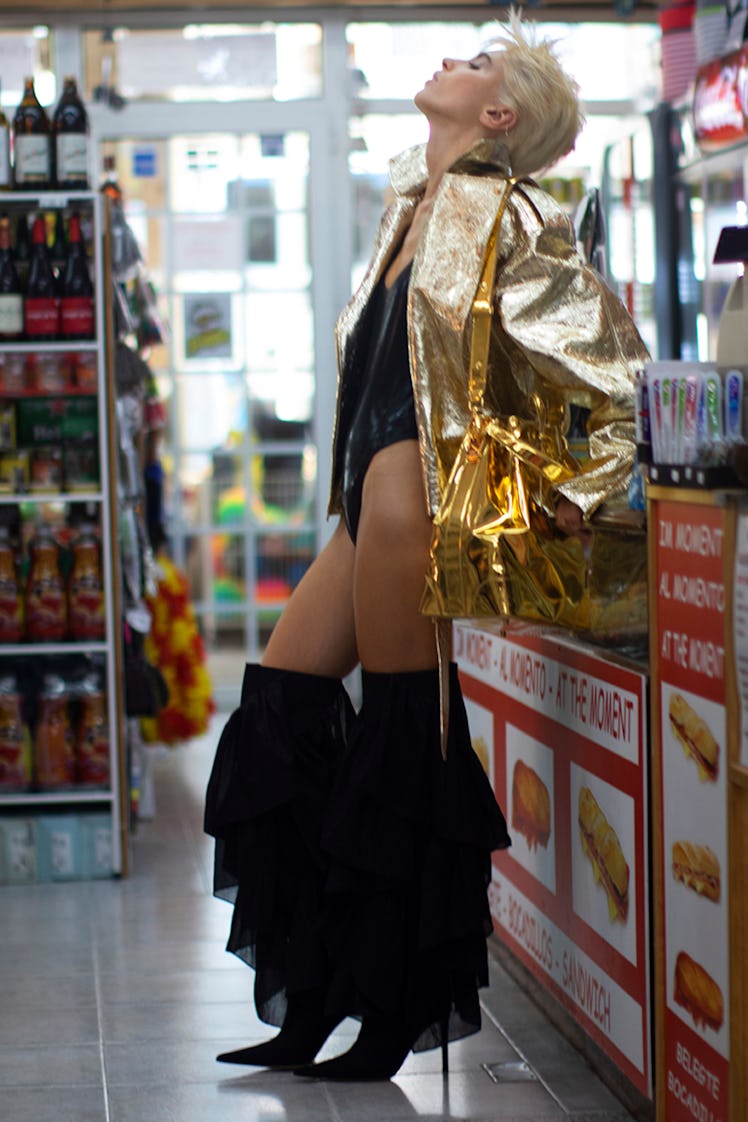 Iris Law wearing gold in a bodega in her Alexandre Vauthier campaign