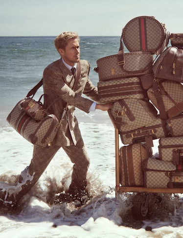 Ryan Gosling pushing an enormous cart of monogram Gucci luggage