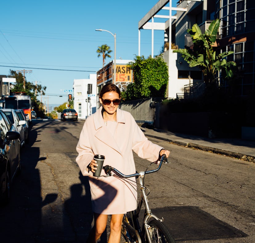 Young woman walking her bike during Mercury retrograde fall 2022, which will affect her zodiac sign ...