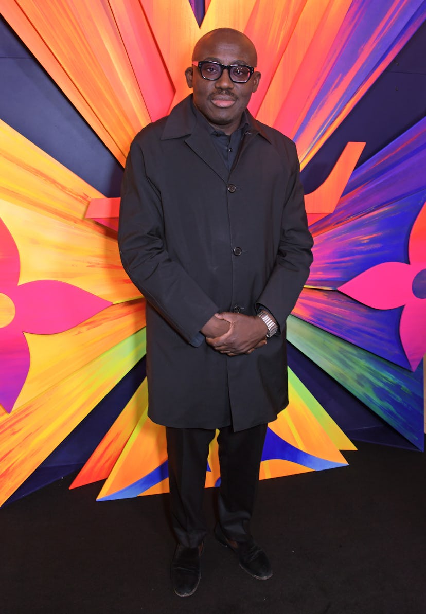 Edward Enninful wearing black and standing against a colorful back drop