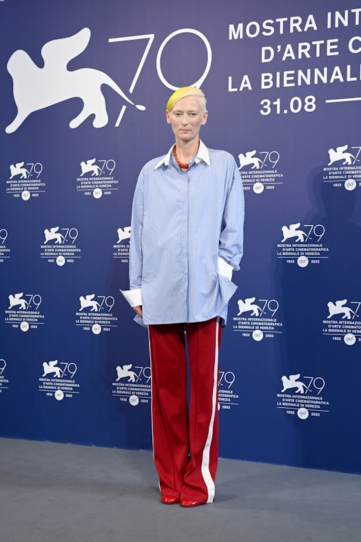 Tilda Swinton wearing a striped blue button-down and red pants at the 2022 Venice Film Festival