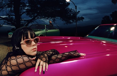 Billie Eilish wearing sunglasses and leaning on a pink car in a Gucci eyewear campaign