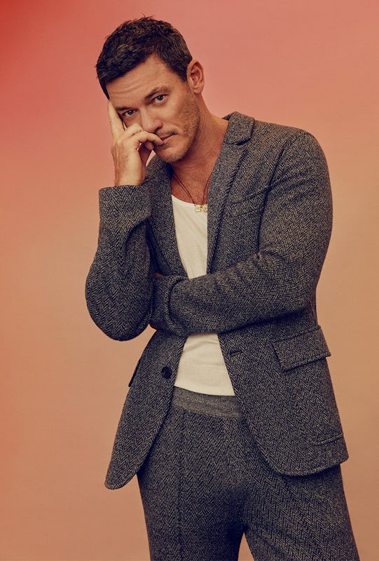 Luke Evans posing with his hand on his face in a Missoni jacket and pants, a Calvin Klein tank top a...