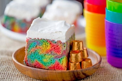 Rainbow poke cake with whipped cream for rainbow baby shower.
