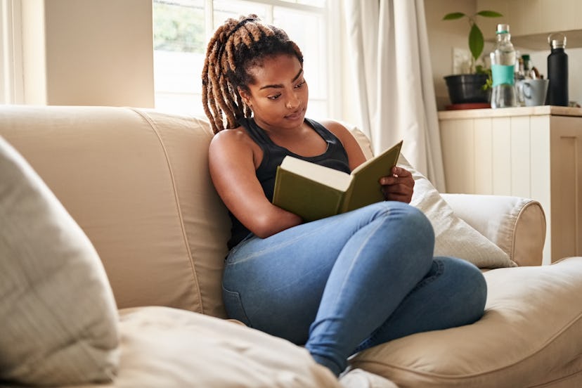 Woman reading a book on the couch.