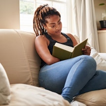 Woman reading a book on the couch.